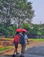 West Java, Indonesia on April 2021. A mother is picking up her child from school, because the weather is very hot they use red umbrellas to protect them from the hot sun. photo