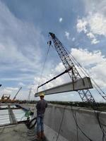 jakarta, indonesia en abril de 2022. un consultor de supervisión está supervisando el trabajo de construcción de vigas con una sola grúa. la viga alzada es una viga prefabricada de hormigón tipo i. foto