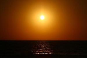 el sol se pone por debajo del horizonte en el mar mediterráneo en el norte de israel. foto