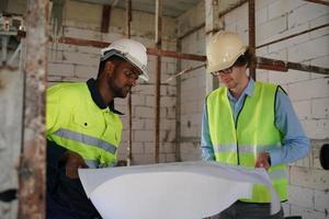 Arquitecto e ingeniero de construcción o agrimensor debaten planes y planos foto