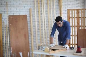 Carpenter grinding joinery product with carvings, finishing woodwork at the carpentry manufacturing photo