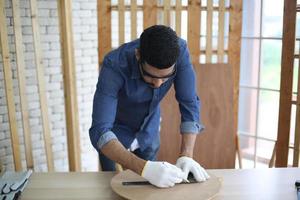 Carpenter grinding joinery product with carvings, finishing woodwork at the carpentry manufacturing photo