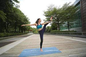 Young attractive woman doing stretching yoga exercise in the park. photo