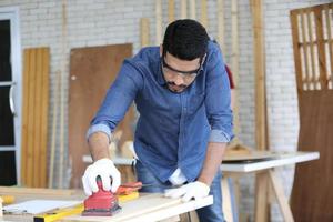 Carpenter grinding joinery product with carvings, finishing woodwork at the carpentry manufacturing photo