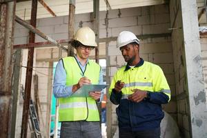 Arquitecto e ingeniero de construcción o agrimensor debaten planes y planos foto