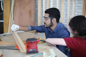 Carpenter grinding joinery product with carvings, finishing woodwork at the carpentry manufacturing photo