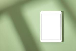 Blank screen tablet mock up and shadow on green pastel background. Copy space. Mock up template. Business communication. Isolated object. Spring decoration. photo