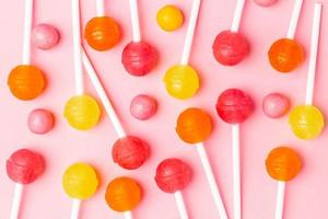 Pink, orange and yellow sweet candy lolipop on a pastel pink background photo