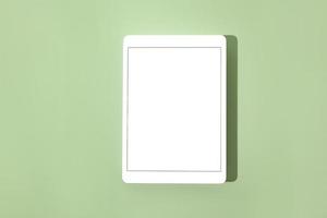 Blank screen tablet mock up and shadow on green pastel background. Copy space. Mock up template. Business communication. Isolated object. Spring decoration. photo