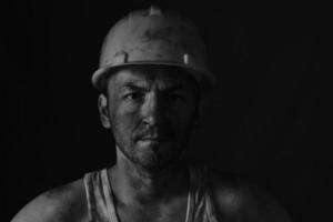 Portrait miner in helmet and undershirt with dirty face. photo