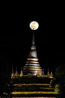 Super moon in night sky and silhouette of ancient pagoda is named Wat Ratchaburana, Phitsanulok in Thailand photo