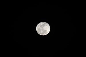 Full moon over dark black sky at night. photo