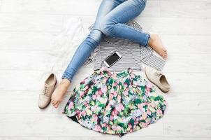 Stylish outfit with accessories and female legs on white wooden background. Top view and copy space photo