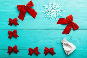 Frame of red bows with winter accessories on blue wooden background. Top view photo