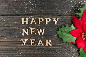 Happy New year 2023 celebration. Wooden text and poinsettia on wooden background. Flat lay. photo