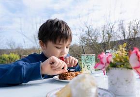 niño hambriento comiendo flapjack para el postre, niño con barras de avena orgánicas veganas caseras con arándanos y semillas, niño comiendo bocadillos y relajándose en el jardín en el día soleado de primavera o verano foto