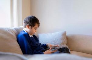 School boy using tablet doing school homework, Kid learning virtual internet online education, Child playing game with digital tablet at home, Cute boy using gadgets for learning photo