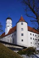 The historic castle in Hoechstaett stands on a hill in front of a blue sky, behind bare trees, in the sunshine photo