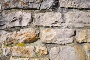 Background of a wall made of natural stones that have been machined and put on top of each other with mortar that is old. photo