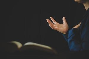 mano doblada en oración a dios en el libro de la santa biblia en el concepto de iglesia para la fe, la espiritualidad y la religión, mujer que ora en la santa biblia por la mañana. mujer católica cristiana mano con adoración de la biblia. foto