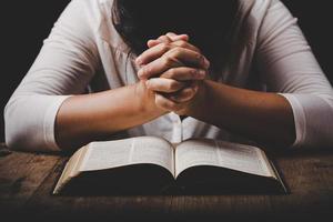 christian woman hand on holy bible are pray and worship for thank god in church with black background, concept for faith, spirituality and religion photo