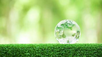 globo planeta cristal en bosque verde con luces de naturaleza bokeh. día Mundial del Medio Ambiente. concepto para la conservación del medio ambiente, proteger la ecología de la tierra y la vida ecológica con espacio de copia foto