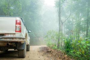 primer plano de camión de ruedas en el paisaje rural con camino embarrado. aventura extrema conduciendo vehículos 4x4 para transporte o viajes o carreras todoterreno en la naturaleza al aire libre. Automóvil de neumáticos 4wd en montaña de tierra. foto