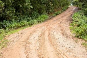 Muddy wet countryside road in Chiang Mai, northern of Thailand. track trail mud road in forest nature rural landscape. brown clay puddle way transport in country photo