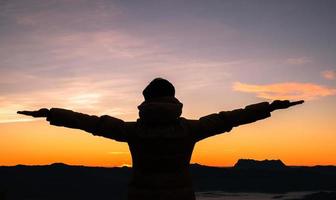 Silhouette of human person hands open palm up worship in sky sunset or sunset. Catholic adult man pray and hope on mountain. Christian religion concept background. fighting and victory for god photo