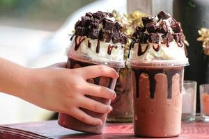 mano sosteniendo una taza de cacao helado, café, cacao, brownies, elegante cafetería