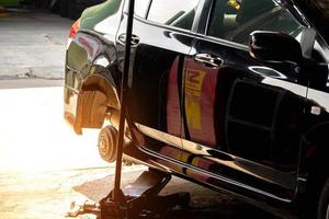 The car jack is lifting the car thicken. while the mechanic removes the tire for repair Repairing tires in the garage, car axles photo