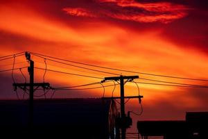 Silhouette of high voltage pole and orange blue sky background on everning day photo