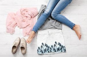 Stylish outfit with accessories and female legs on white wooden background. Top view and copy space photo