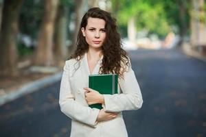 el retrato de una mujer de negocios con un cuaderno en la mano. chica elegantemente vestida afuera. exitosa mujer europea blanca foto