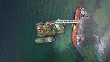 Rescue ship with crane lifting wrecked cargo ship at port in Odessa video