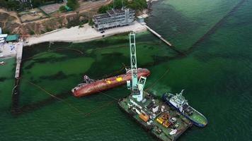 navio de resgate com guindaste levantando navio de carga destruído no porto de odessa video