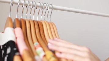 Person browsing clothes hanging on a rack video