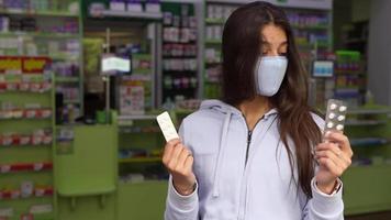 Woman wearing a mask holds and show medication at pharmacy video