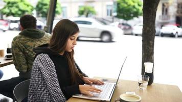 Woman at coffee shop works and studies on laptop video