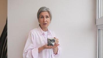 Woman drinks tea from a mug and talks to camera video