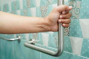 Asian woman patient use toilet support rail in bathroom, handrail safety grab bar, security in nursing hospital. photo