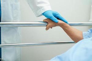 Asian elder senior woman patient holding bed rail while lie down with hope waiting her family in hospital. photo