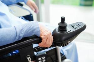 Asian elderly woman disability patient sitting on electric wheelchair in park, medical concept. photo