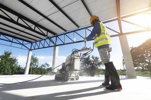 Construction workers use a machine to polish and finish surfaces or epoxy concrete on the home site.