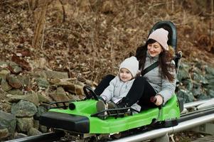 Mother with daughter ride electric sleigh on rails. photo