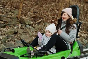 Mother with daughter ride electric sleigh on rails. photo