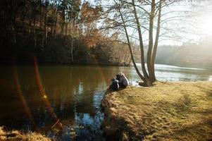 Mother with kids fishing with a stick in pound at early spring park. photo