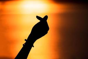 Silhouette hand in mini heart shape with sunset,Love concept. Happy Valentine's Day photo