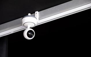 modern white surveillance camera, mounted on the ceiling in the living room, to record the events that take place. photo