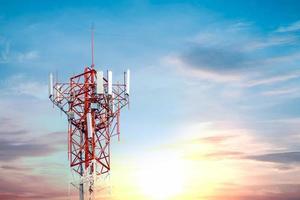 red telephone tower with many signal on sky and white clouds background taken in the evening The sun is going down the horizon photo